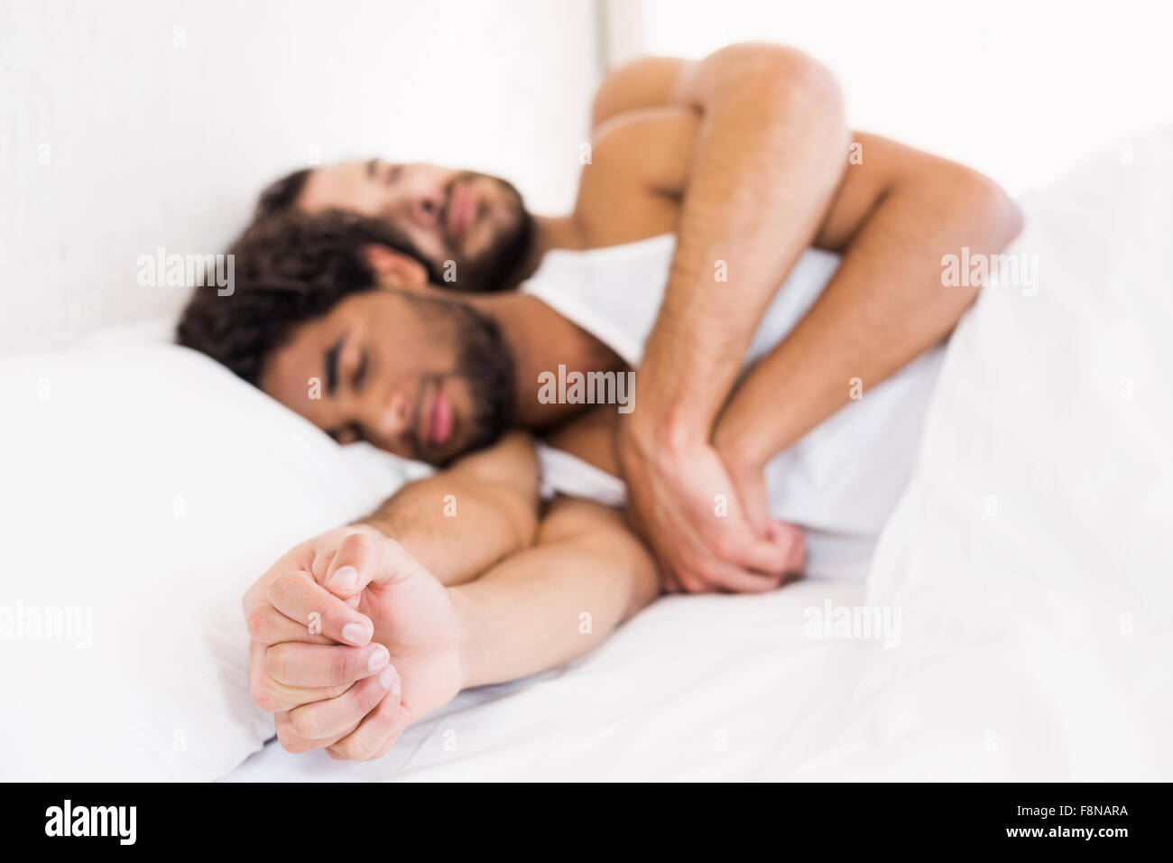 Gay couple sleeping together on bed Stock Photo