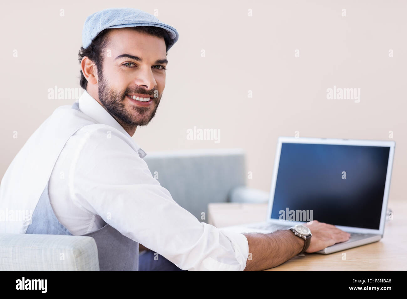 Smiling man using laptop looking back at the camera Stock Photo