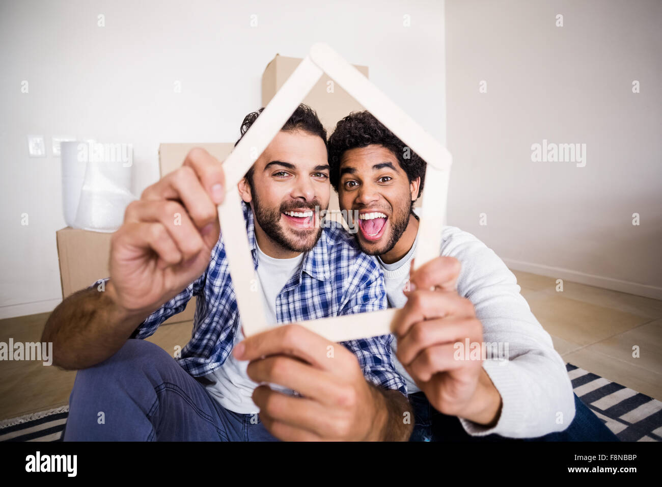 Happy gay couple holding house outline Stock Photo