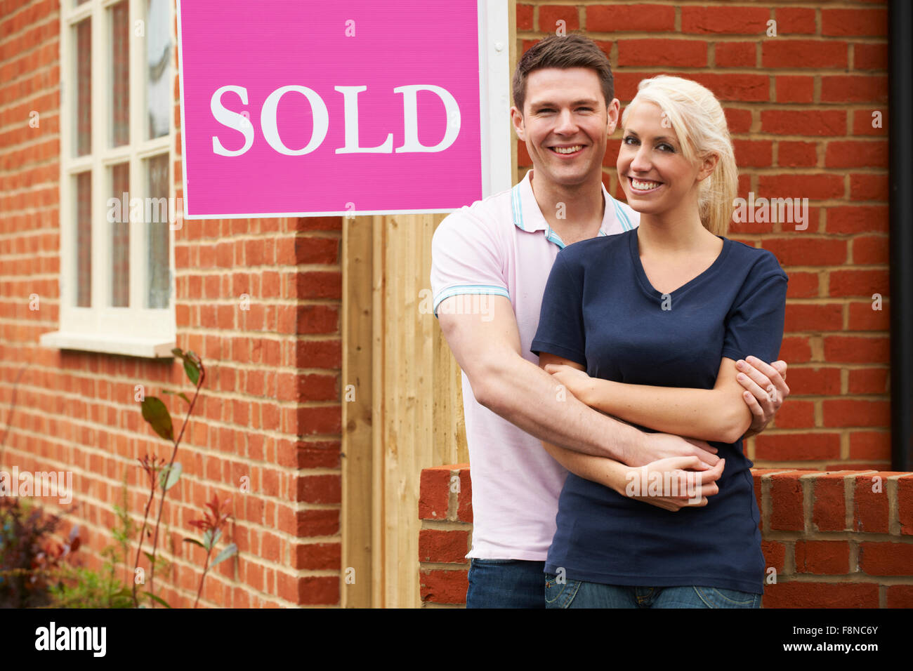 Happy Young Couple Standing Next to Sold Sign Outside New Home Stock ...