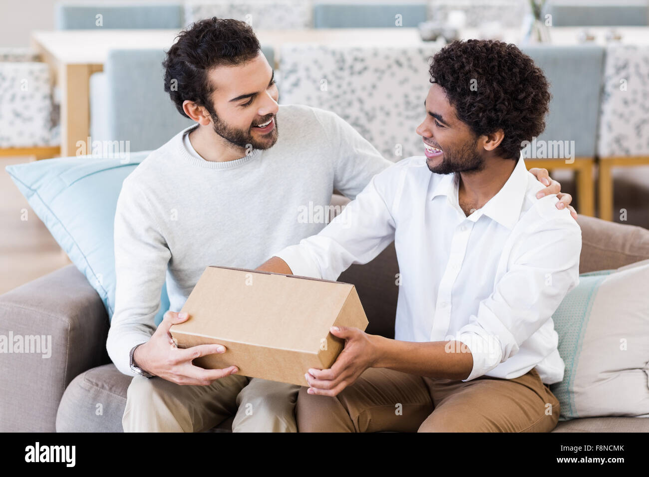 Happy gay couple holding box Stock Photo - Alamy