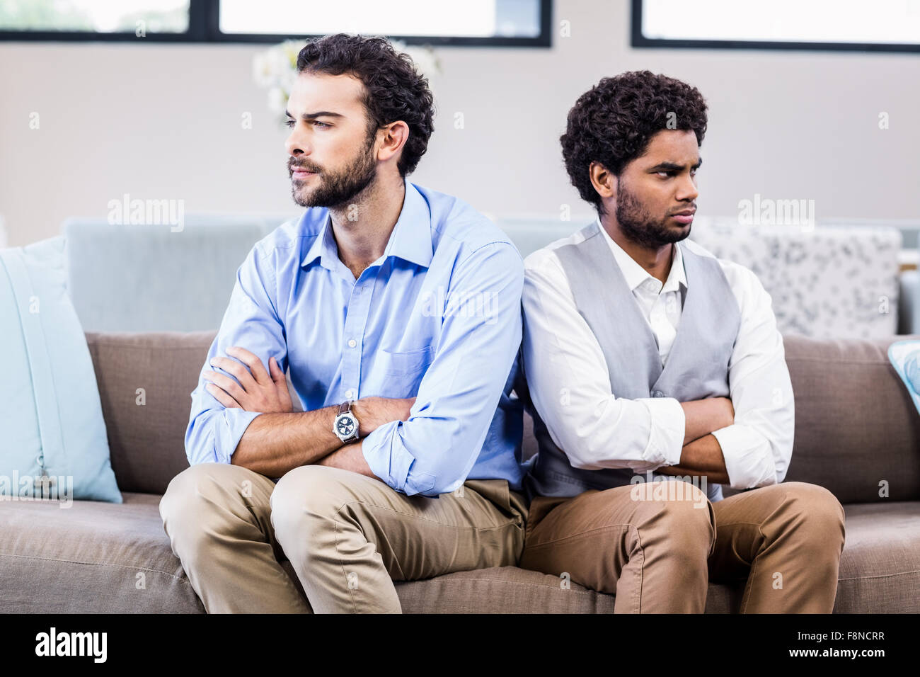Gay couple sitting back-to-back after arguing Stock Photo