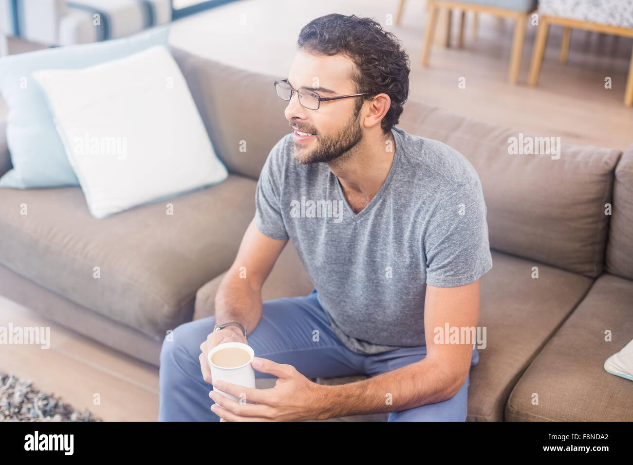 Handsome man on sofa holding coffee Stock Photo