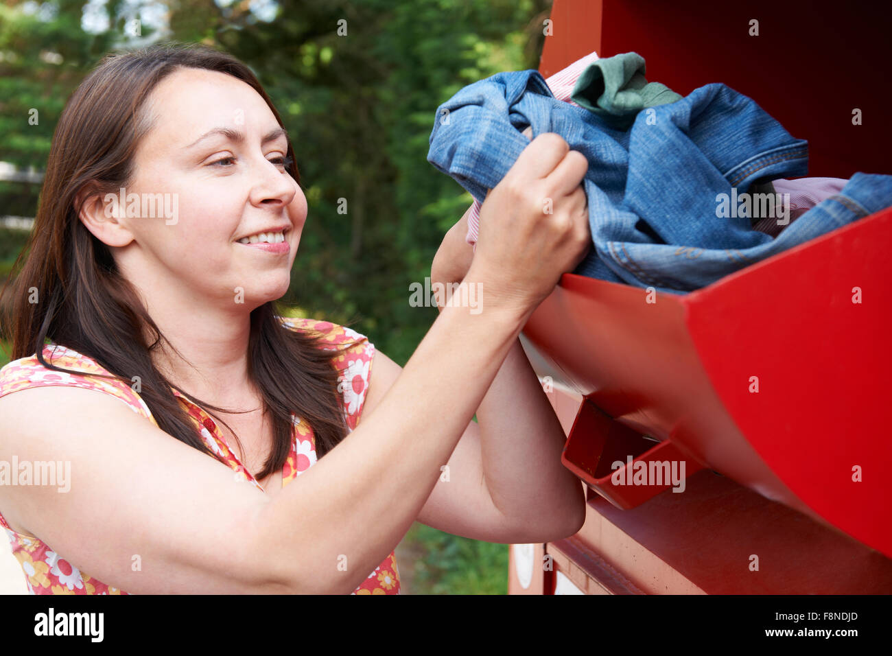 Woman Putting Old Clothes Into Recycling Bank Stock Photo Alamy