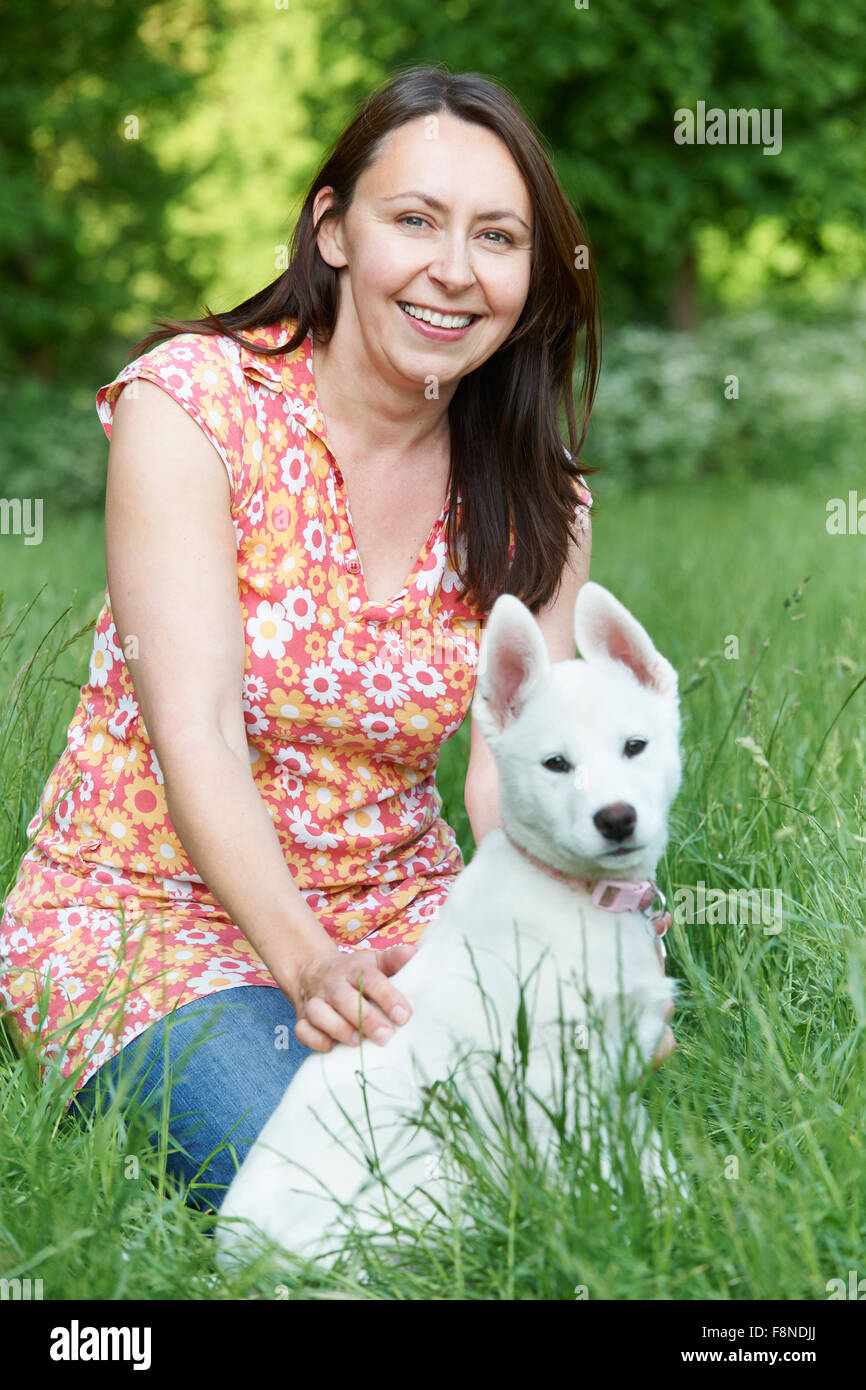 Mature Woman Exercising Dog In Countryside Stock Photo