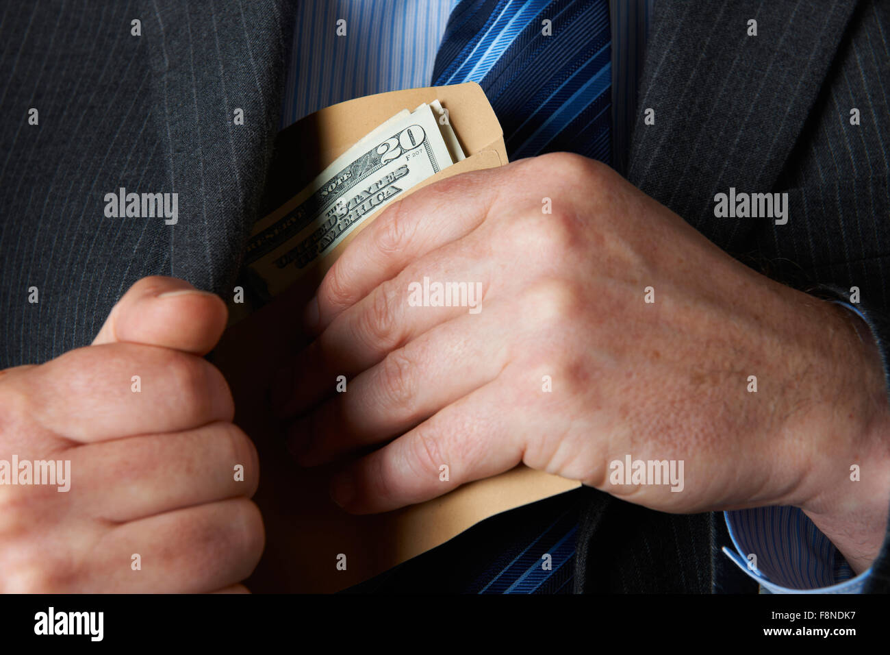 Businessman Putting Envelop of Dollars In Pocket Stock Photo