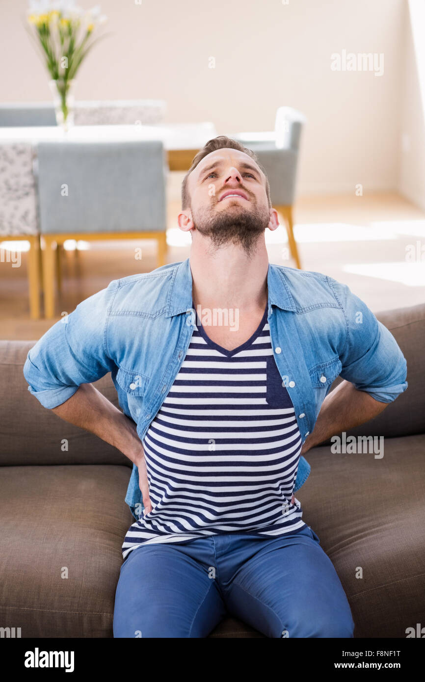 Handsome man with back pain on sofa Stock Photo