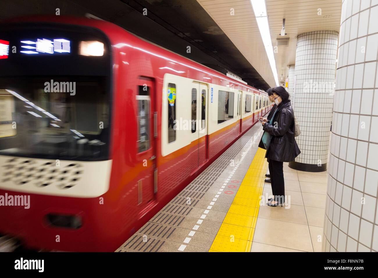 A Japanese woman waiting in the underground for a passing train Stock Photo