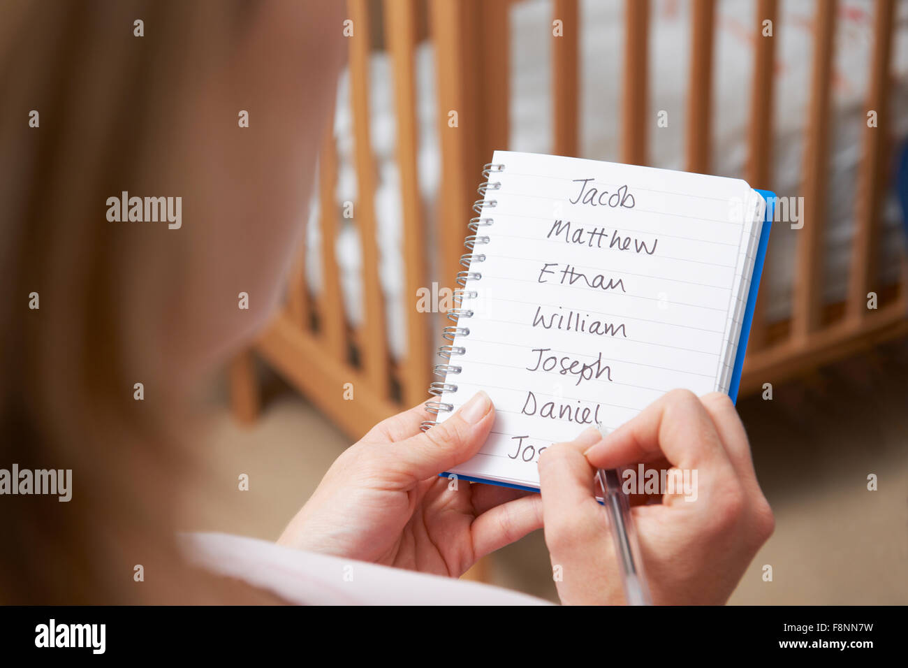 Woman Writing Possible Names For Baby Boy In Nursery Stock Photo