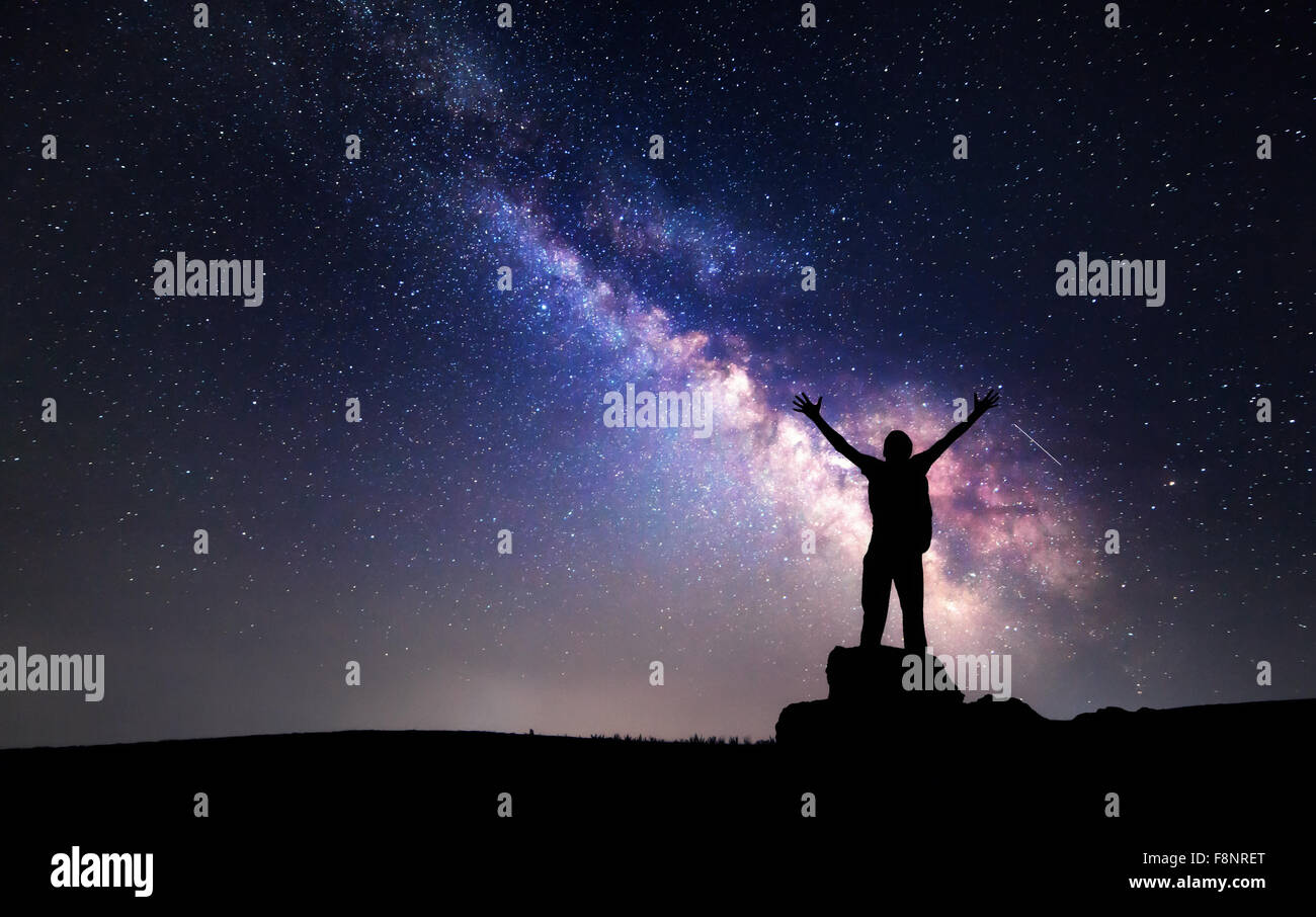 Milky Way. Night sky with stars and silhouette of a man with raised-up ...