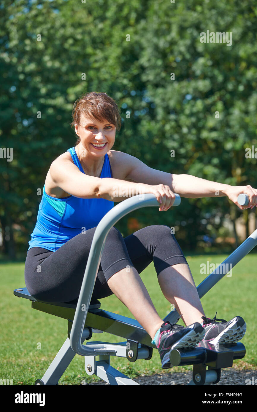 Mature Woman Exercising On Rowing Machine In Park Stock Photo