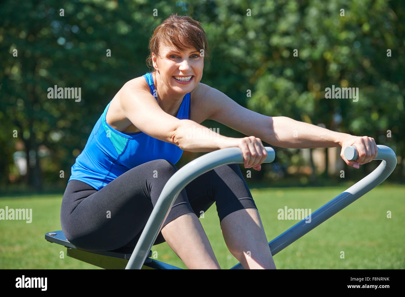 Mature Woman Exercising On Rowing Machine In Park Stock Photo