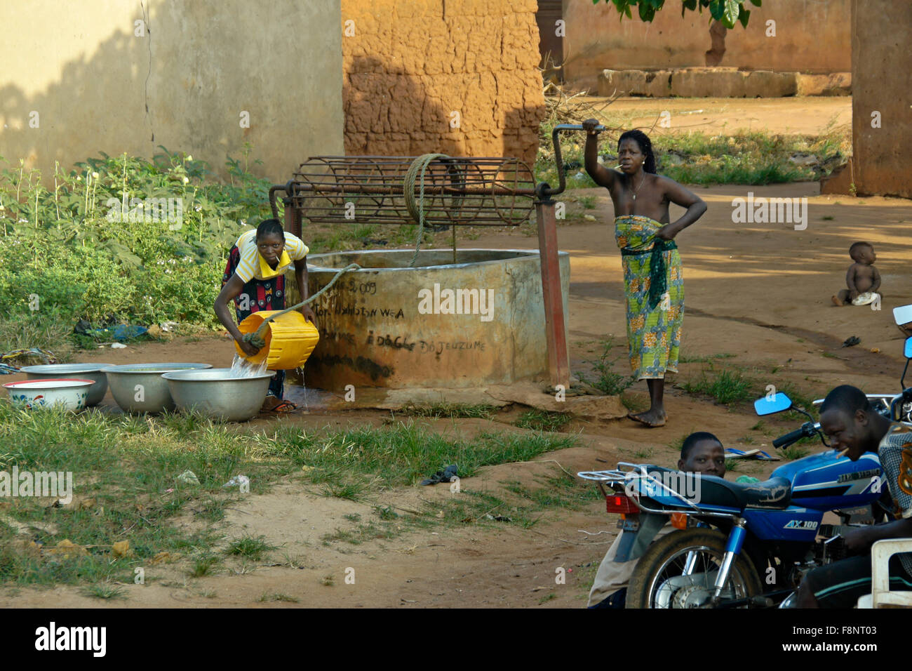Village women fetching water from community well, Benin Stock Photo