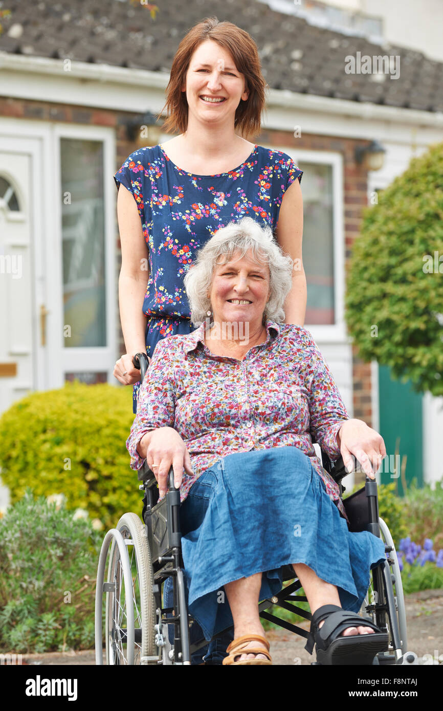 Adult Daughter Pushing Mother In Wheelchair Stock Photo