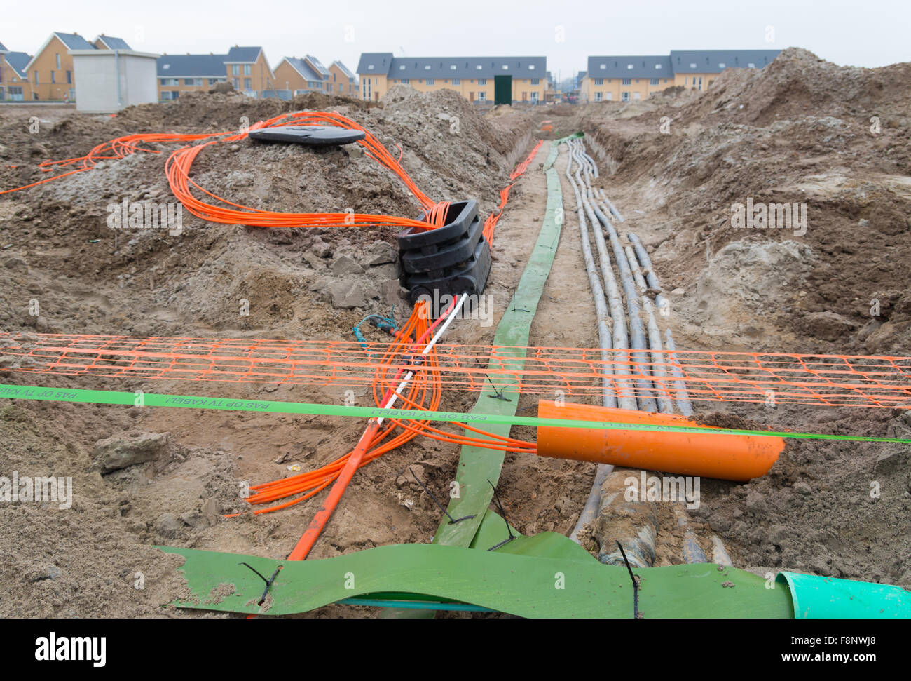 orange and green cables in the ground. The text on the green band says: watch out television cable Stock Photo