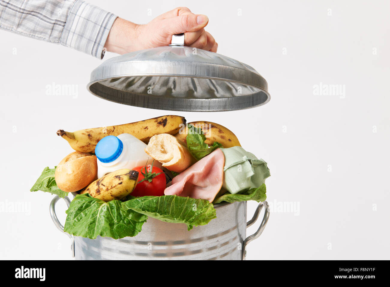 Hand Putting Lid On Garbage Can Full Of Waste Food Stock Photo