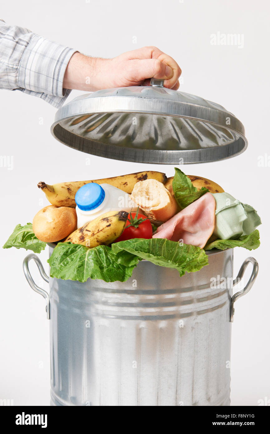 Hand Putting Lid On Garbage Can Full Of Waste Food Stock Photo