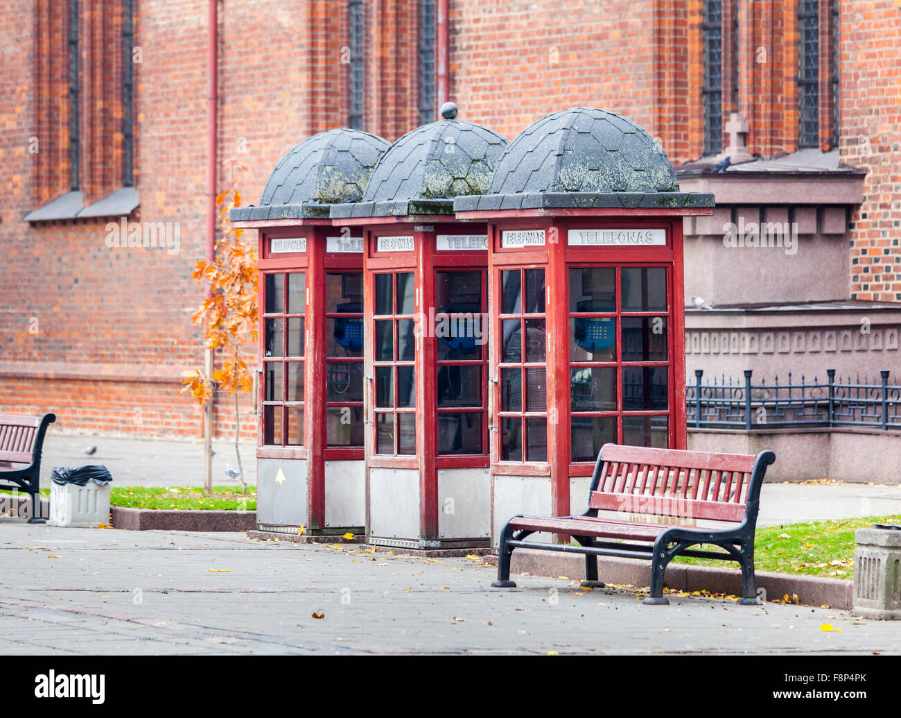 Street scene: row of three traditional style, old-fashioned faded roadside red telephone boxes in Kaunas, the second city of Lithuania Stock Photo