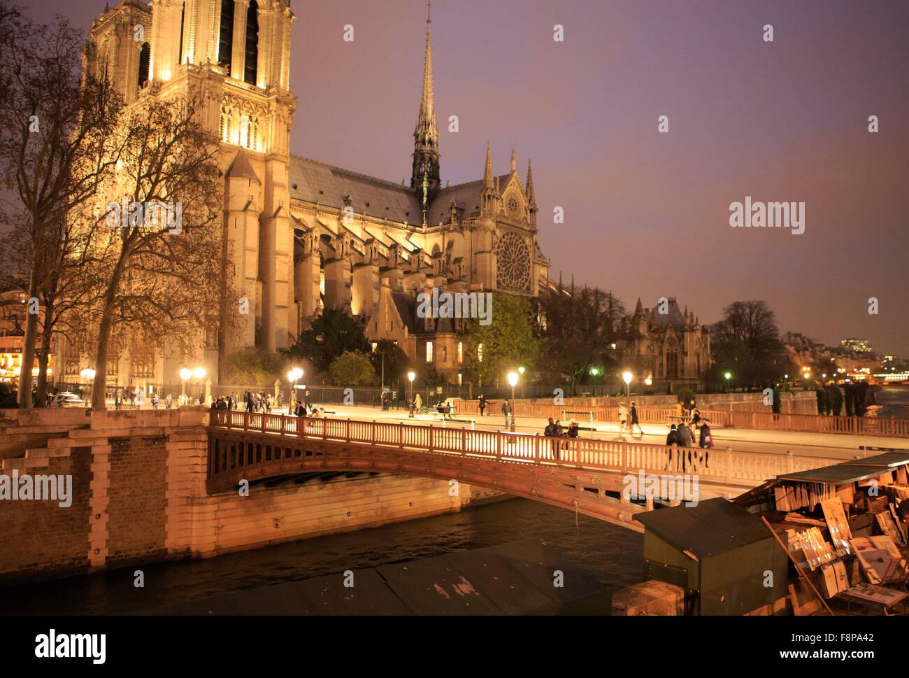 Tourists cross a bridge over a canal towards the Notre Dame Cathedral