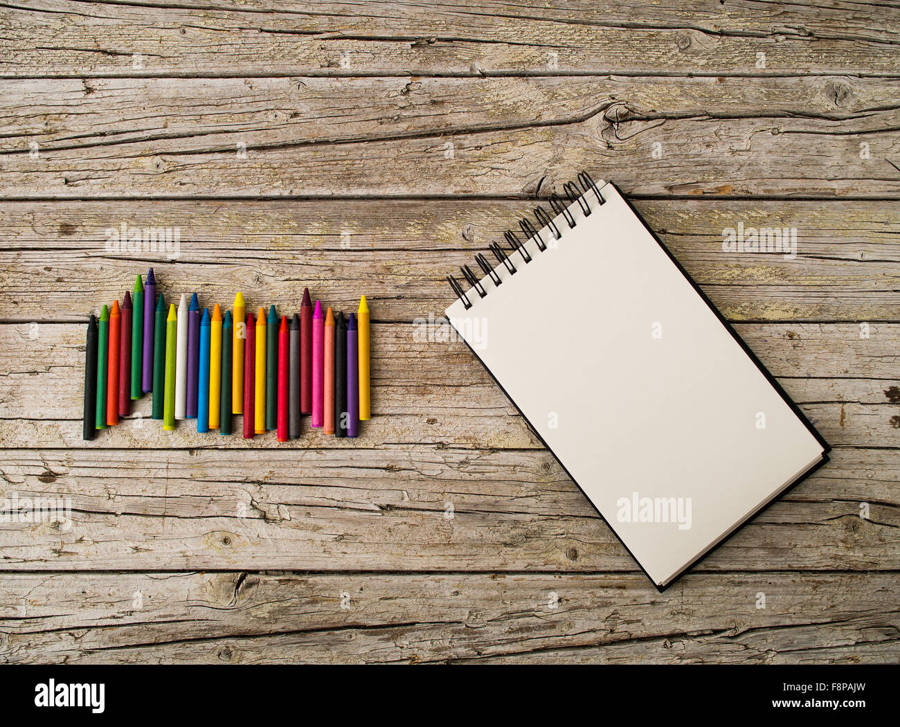 https://c8.alamy.com/comp/F8PAJW/colorful-wax-pencils-and-notebook-on-wooden-background-F8PAJW.jpg