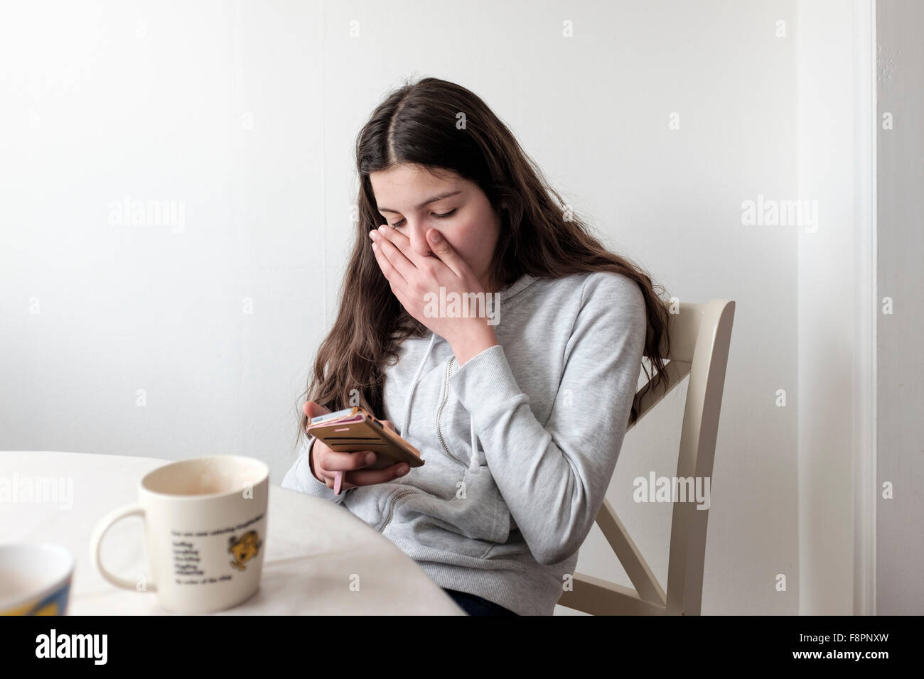 Teenage girl reading  on mobile phone,looking embarrassed Stock Photo