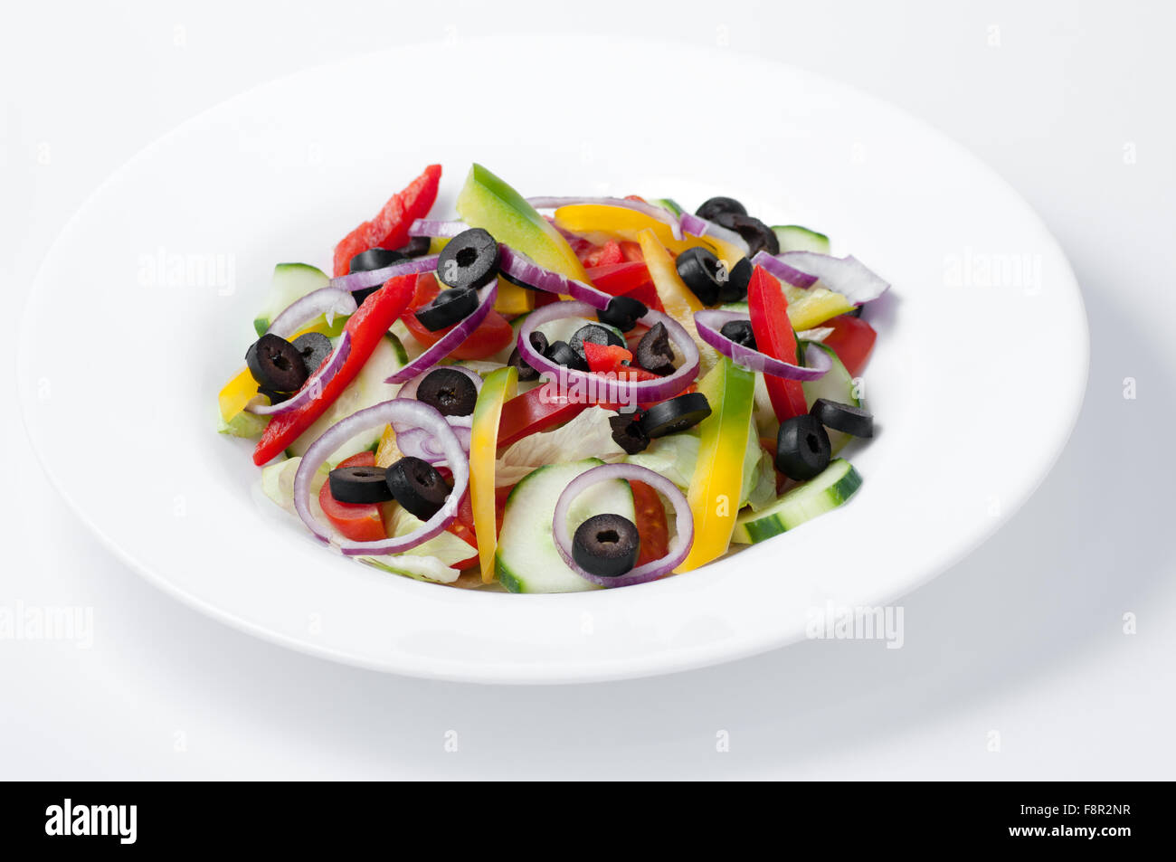 close-up of mixed, raw vegetables: cut-up red and yellow peppers, slices of cucumbers, onion rings, slices of black olives and t Stock Photo