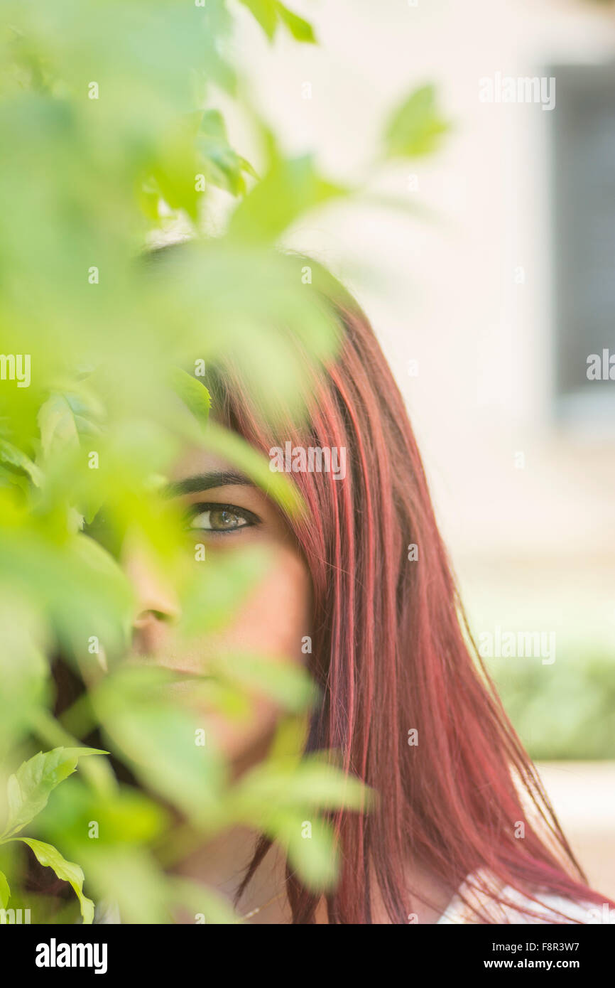 Young woman peeking through the leaves outdoors Stock Photo