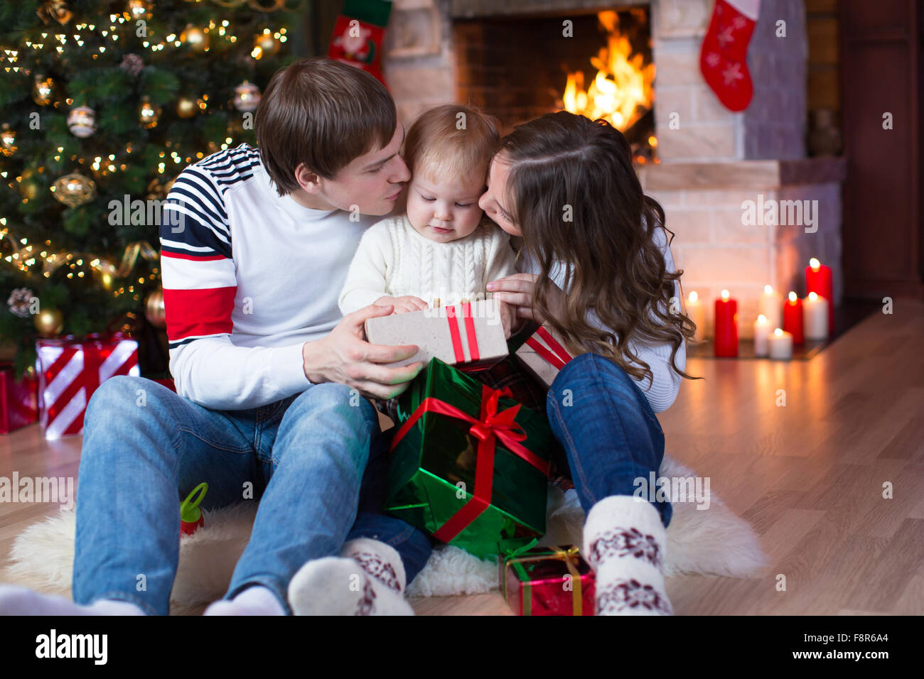 Happy parents kissing little son and giving gifts on Christmas and New Year Stock Photo