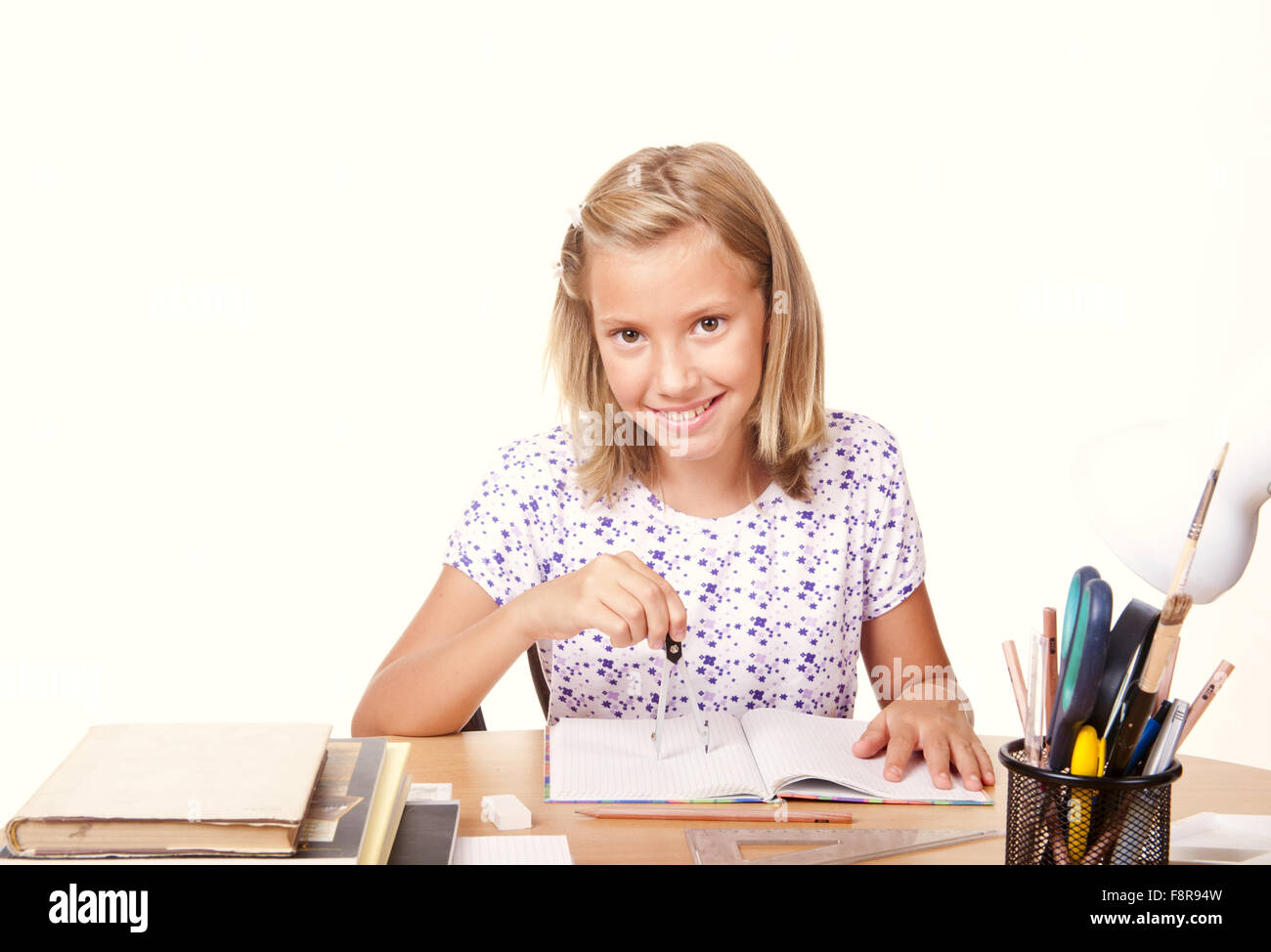 Happy Young School Girl Sitting At The Table With A Ruler And Draw