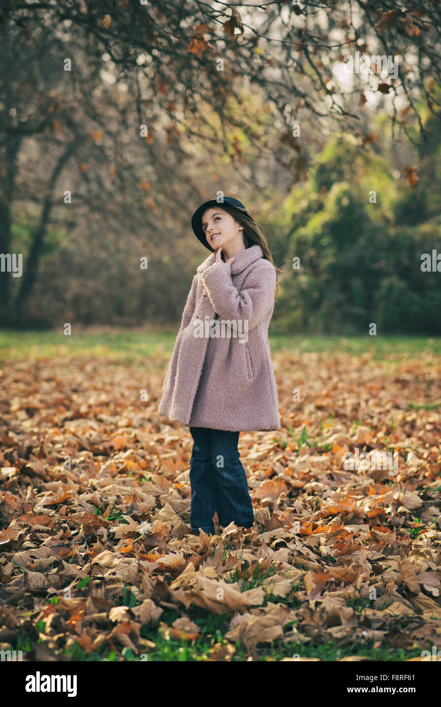 Portrait of a girl looking thoughtful, standing in autumn leaves Stock Photo