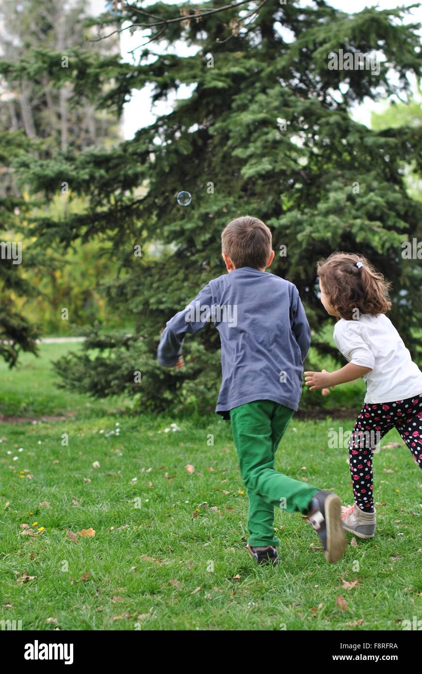 Boy and girl chasing soap bubbles Stock Photo