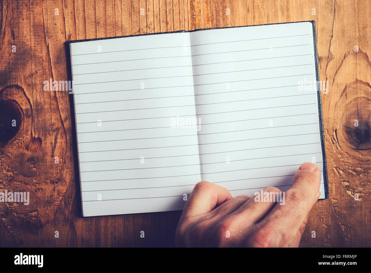 Top view of male hand flipping blank notebook pages, retro toned, selective focus Stock Photo