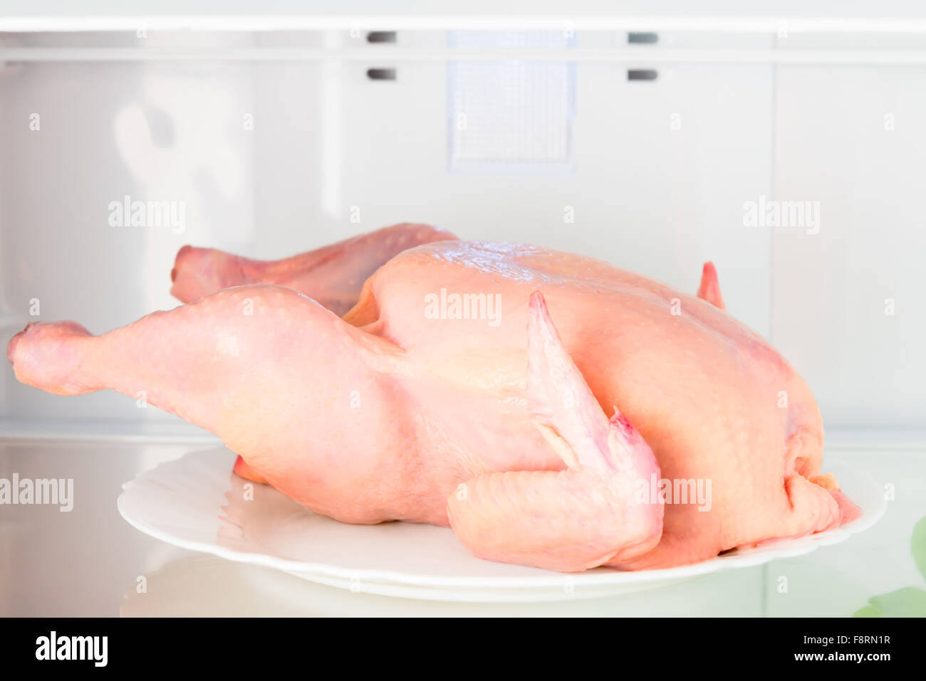 raw chicken on the shelf of the refrigerator on a plate closeup Stock Photo