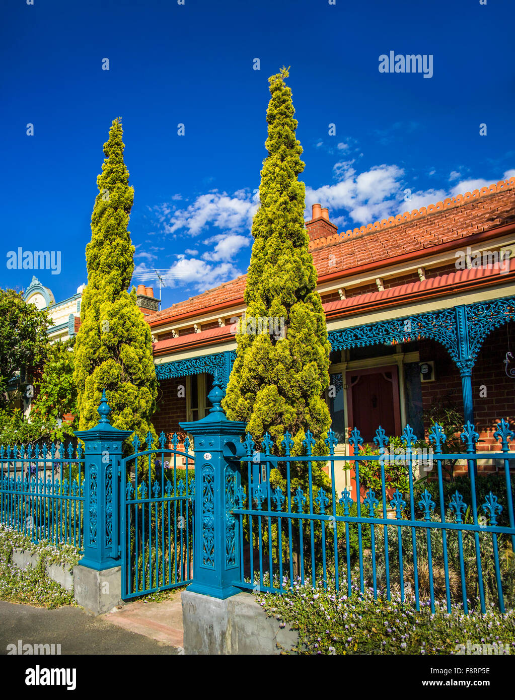 Period single storey red brick house with blue painted ironwork fence