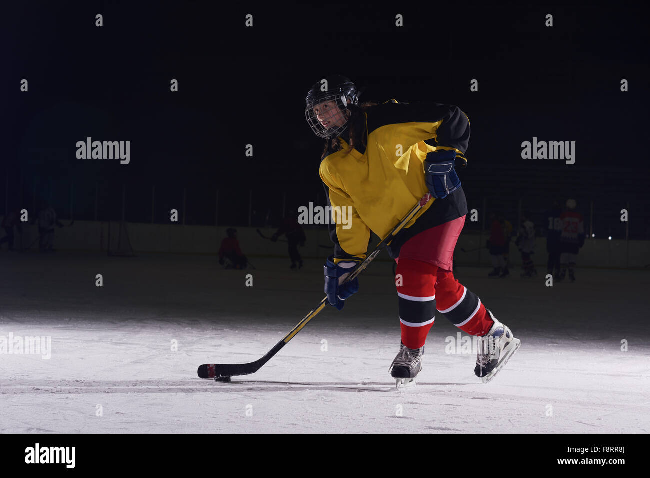 teen girl children ice hockey player in action kicking puck with stick