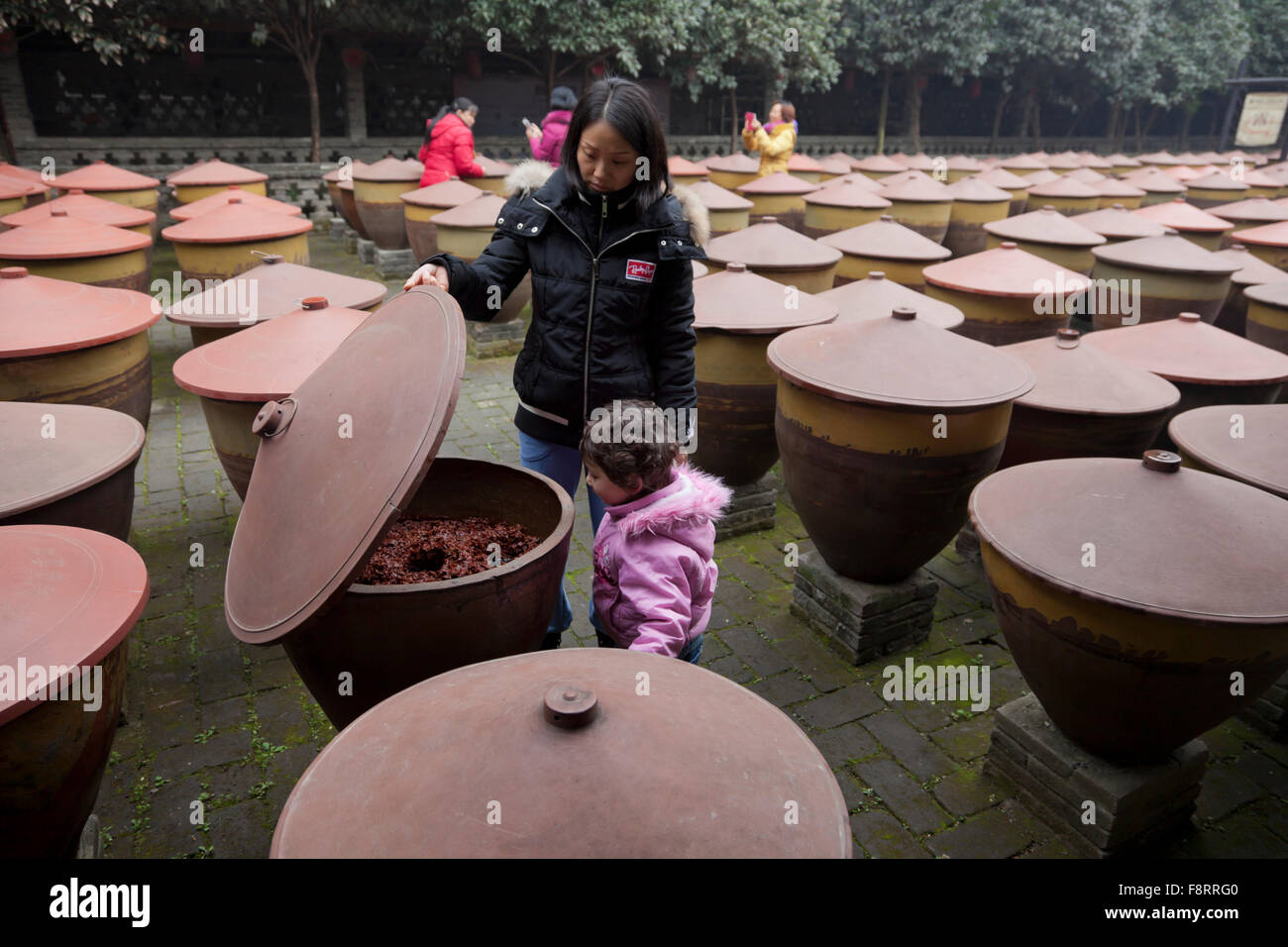 A visitor explores the earthenware jars with plastic lids holding Pixian chilli bean past as it matures in a factory in Chengdu Stock Photo