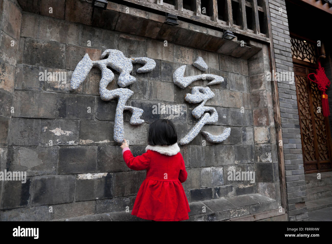 A toddler examine the Chinese characters "kuan zhai" made from plaster