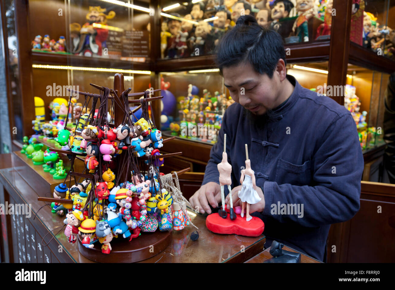 A man makes colourful souvenirs or mementos at a booth in the old quarter of Kuan Zhai Alley in Chengdu. Stock Photo