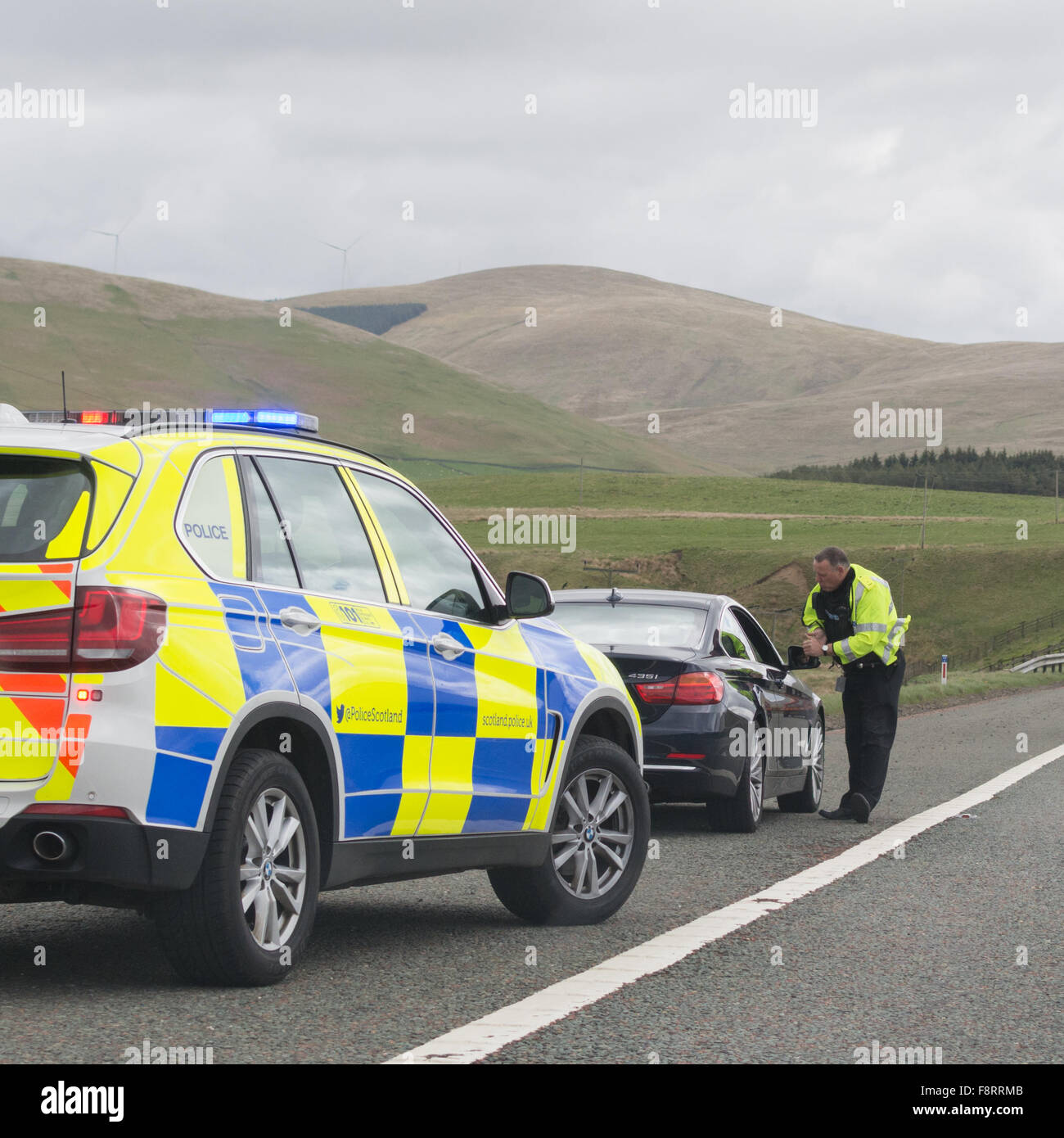 Motorist pulled over by the side of southbound M74 motorway by police officer in patrol car - Scotland, UK Stock Photo