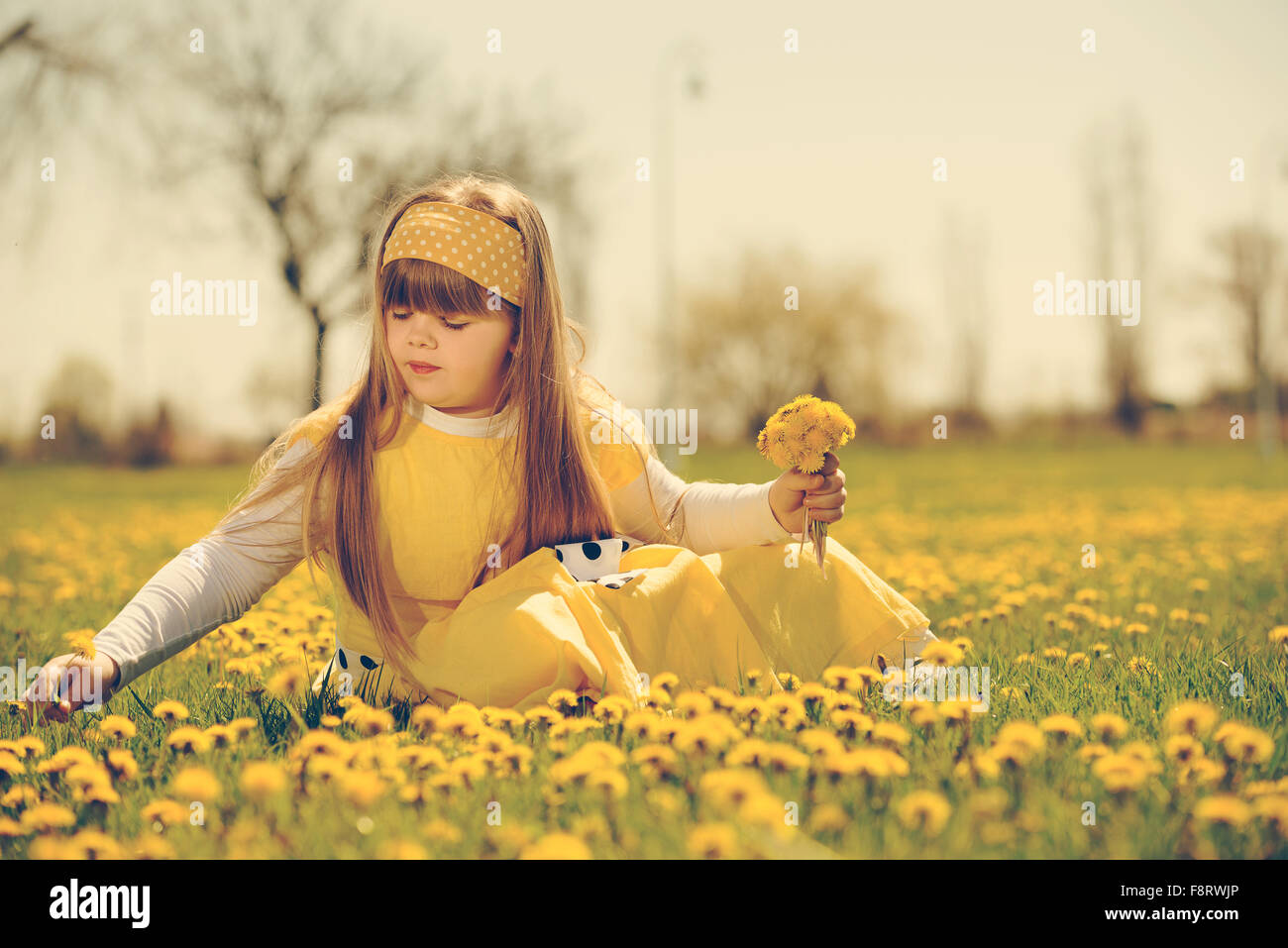 little girl enjoying the sunny spring day in fields flowers. vintage-look Stock Photo