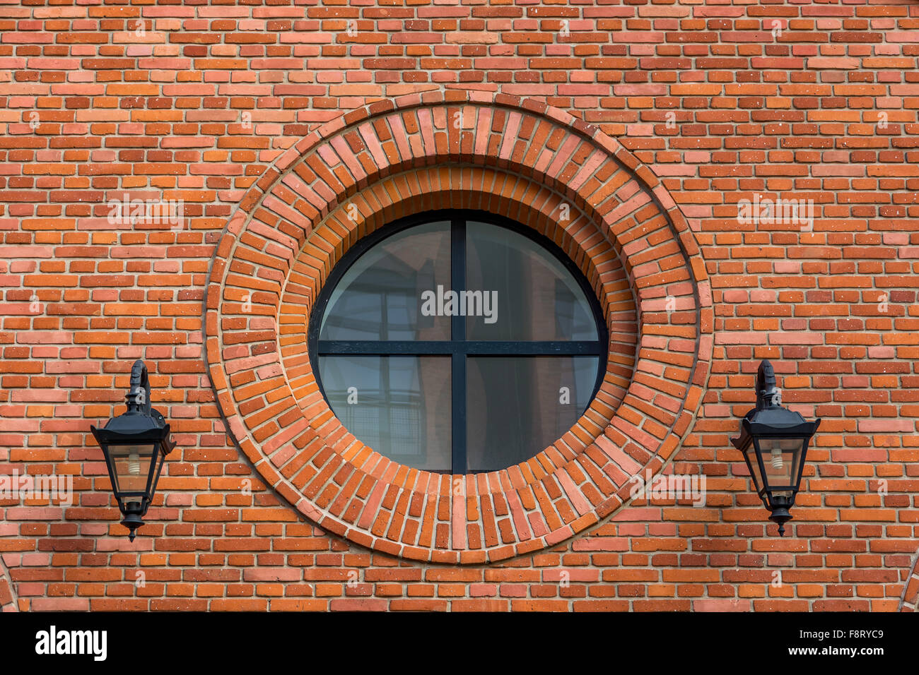 Beautifully renovated wall of an old textile factory with round window and two lanterns Stock Photo