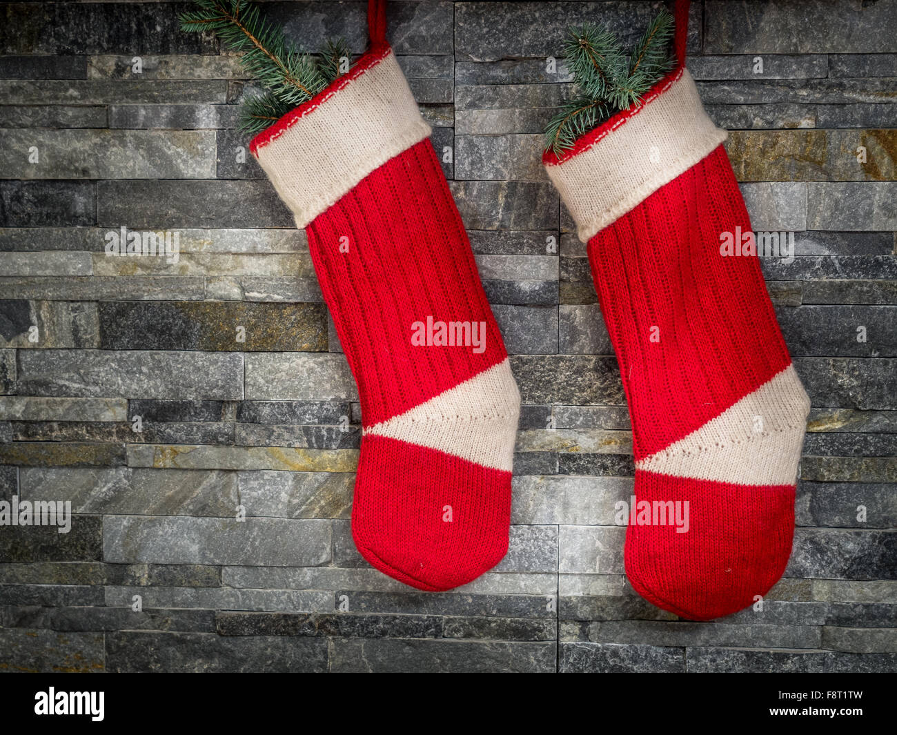 Pair of red Santa stocking hanging on stone wall Stock Photo