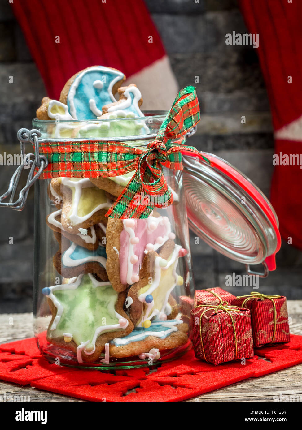 Assorted Christmas gingerbread cookies with colorful icing in glass jar on table Stock Photo