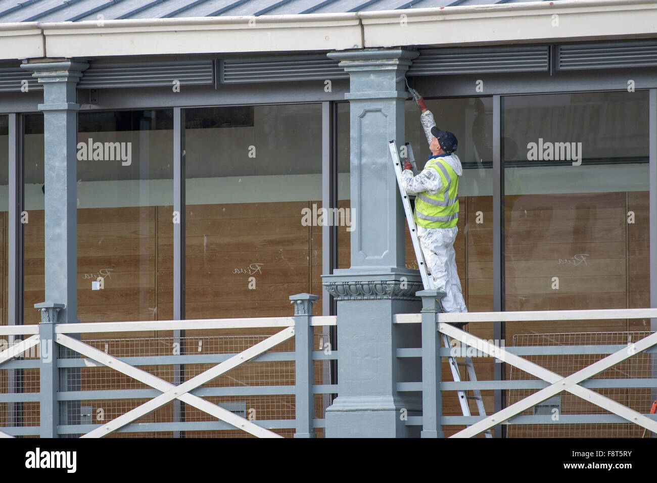 A painter and decorator painting a pillar on Town Pier in Gravesend, Kent. Stock Photo