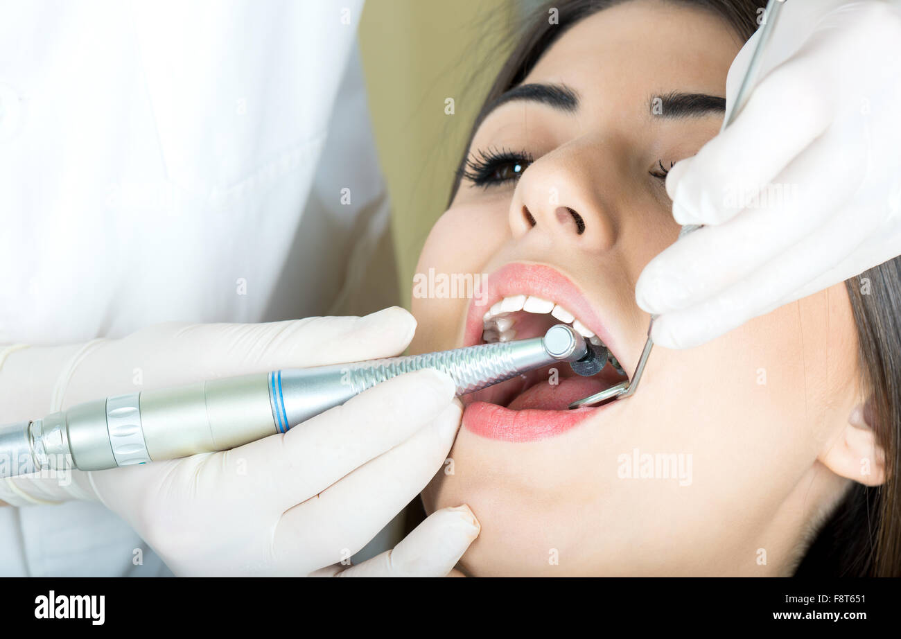 young women to the dentist in the dental chair sits next to a doctor to do the dentist to see if his teeth were okay Stock Photo