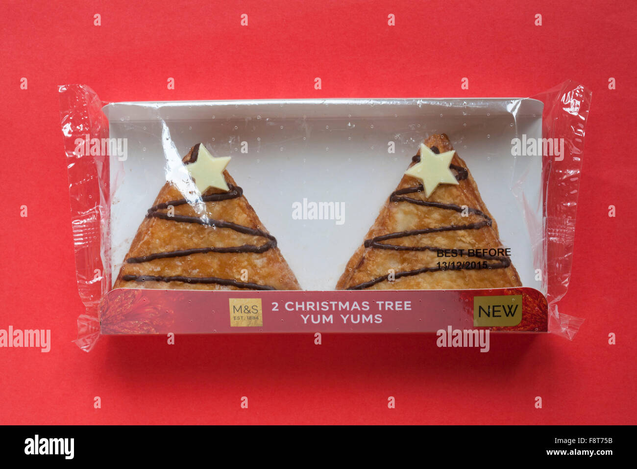 Packet of M&S 2 Christmas Tree Yum Yums iced doughnuts filled with toffee sauce isolated on red background Stock Photo