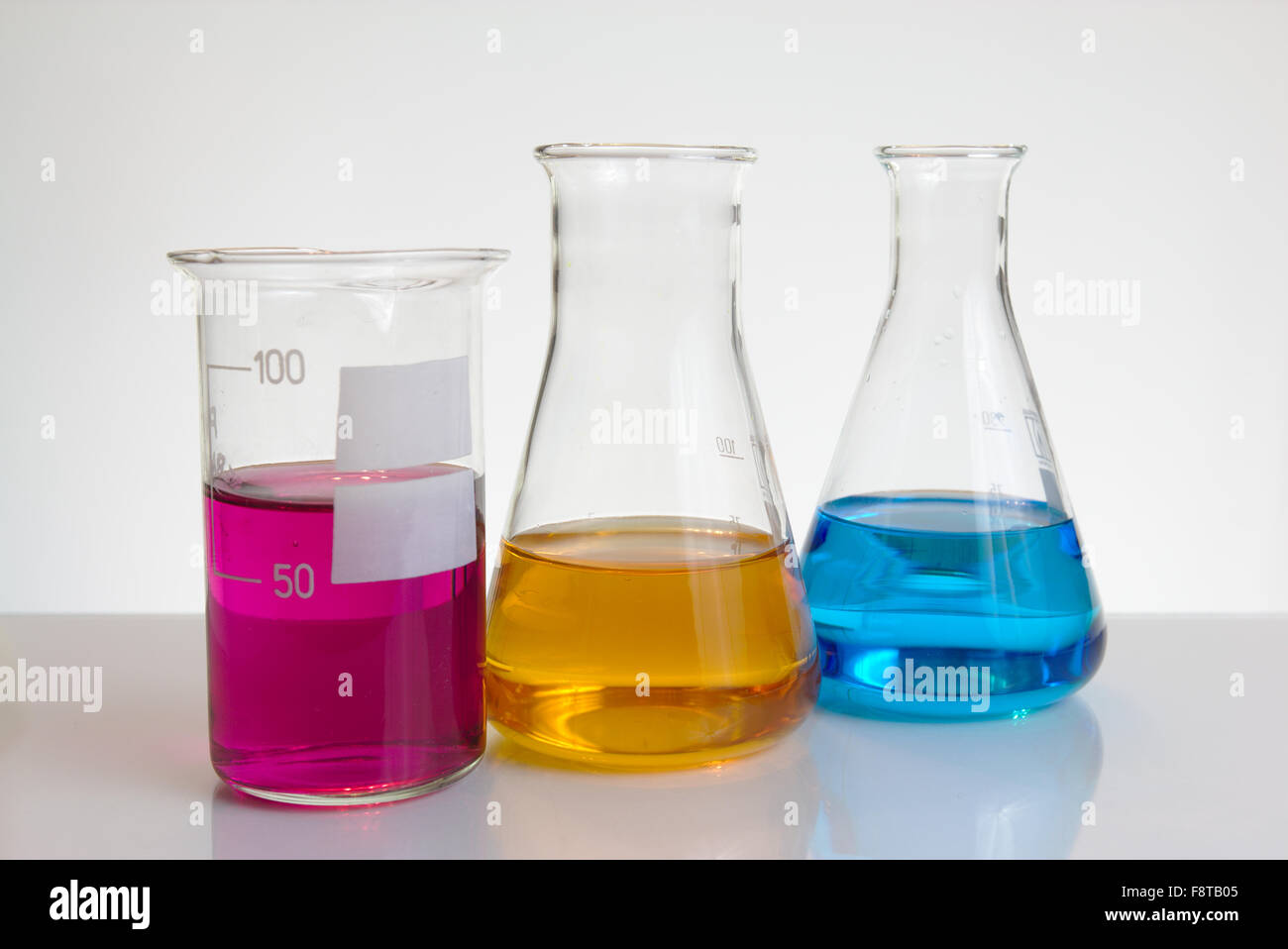 Three colour salt solutions in laboratory glassware Stock Photo