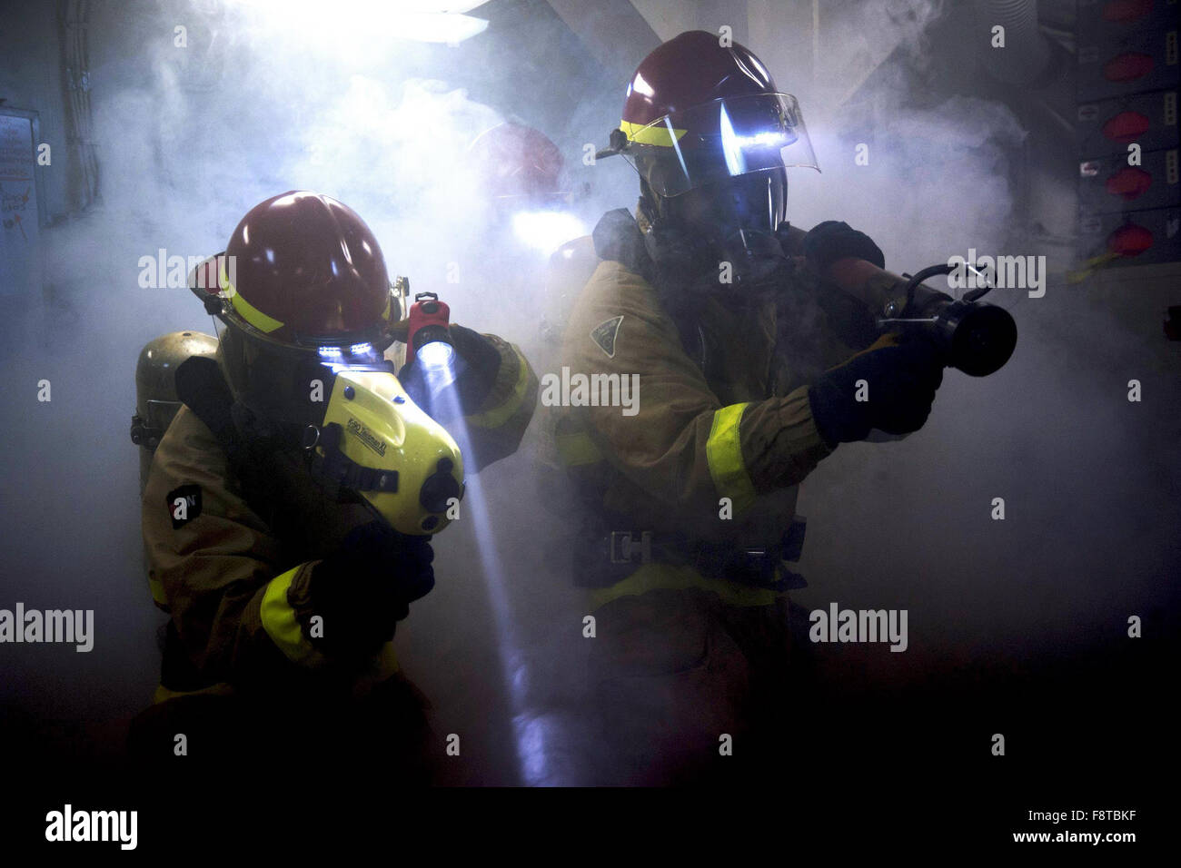 Damage Controlman 3rd Class R. Berens, left, and Damage Controlman D. Barber fight a simulated fire during a drill aboard the aircraft carrier USS Harry S. Truman Stock Photo