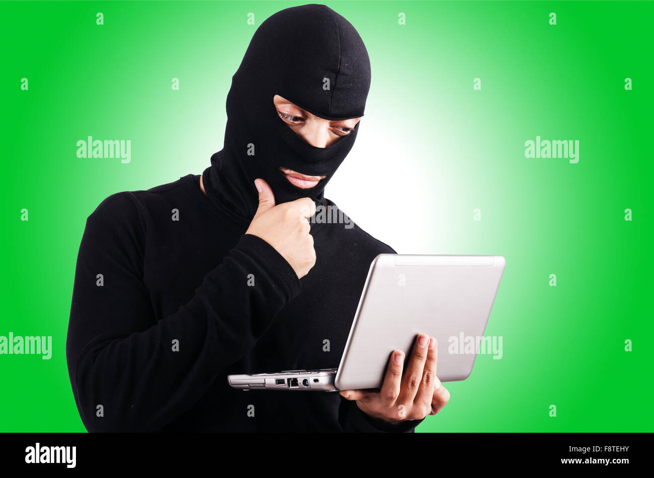 Hacker with computer wearing balaclava Stock Photo - Alamy