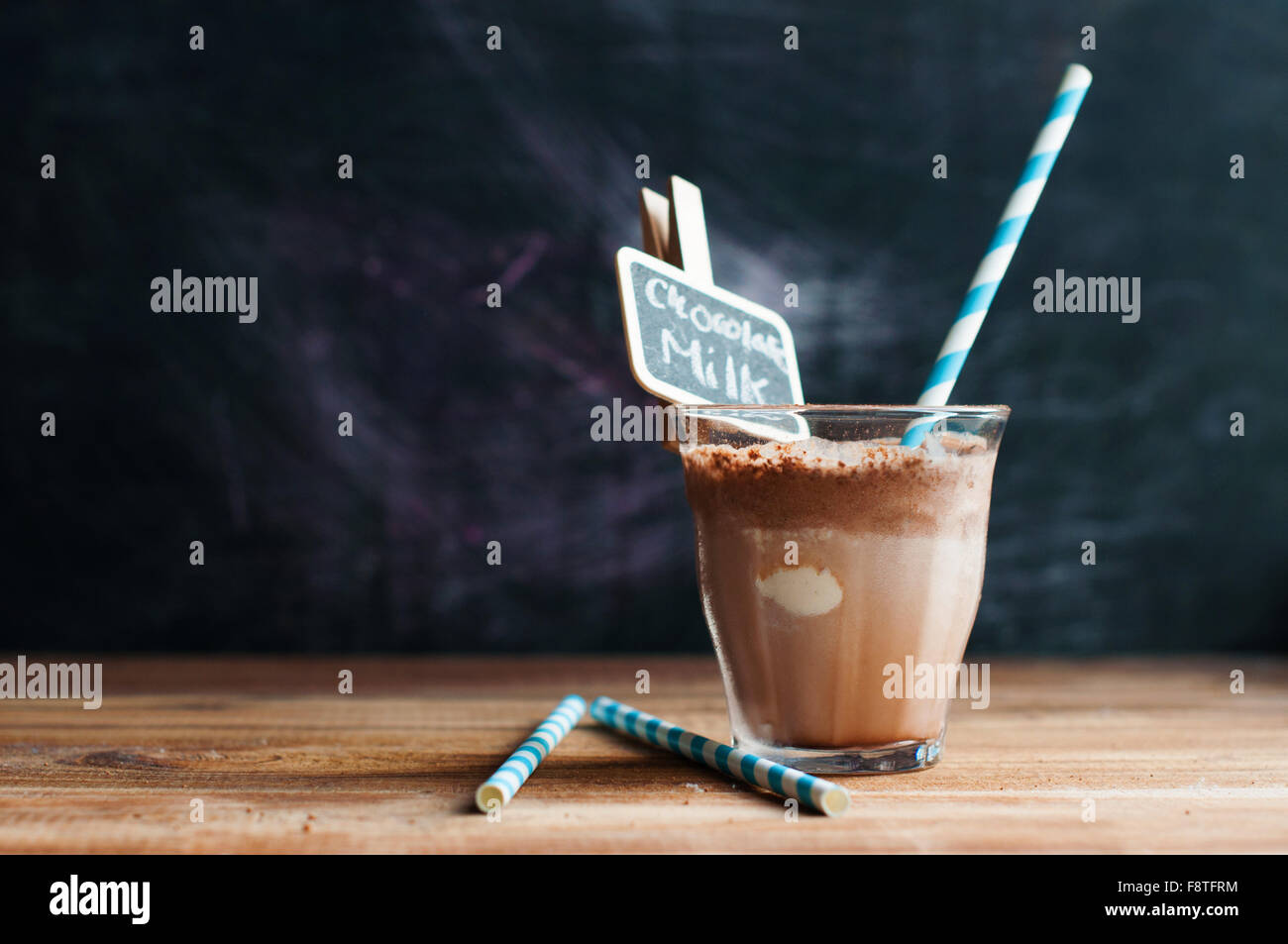 Hot chocolate with milk froth on a wooden background with paper straw